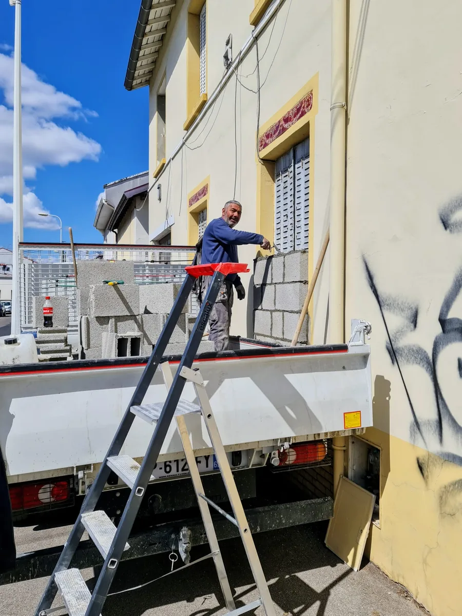 Ion Pavel, gérant de SRN Rénovation, montant un mur en parpaings sur un chantier de maçonnerie à Vénissieux