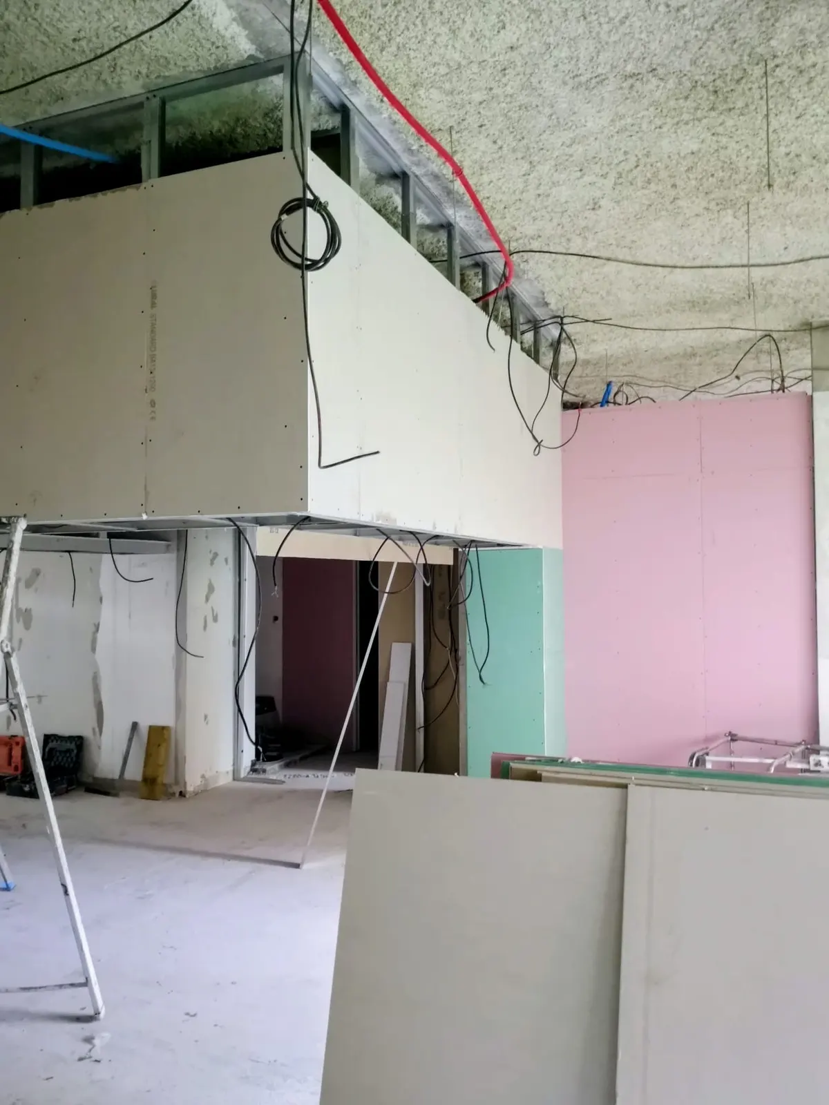 Cloisons et mezzanine en plaques de plâtre de couleurs variées dans un grand local en rénovation