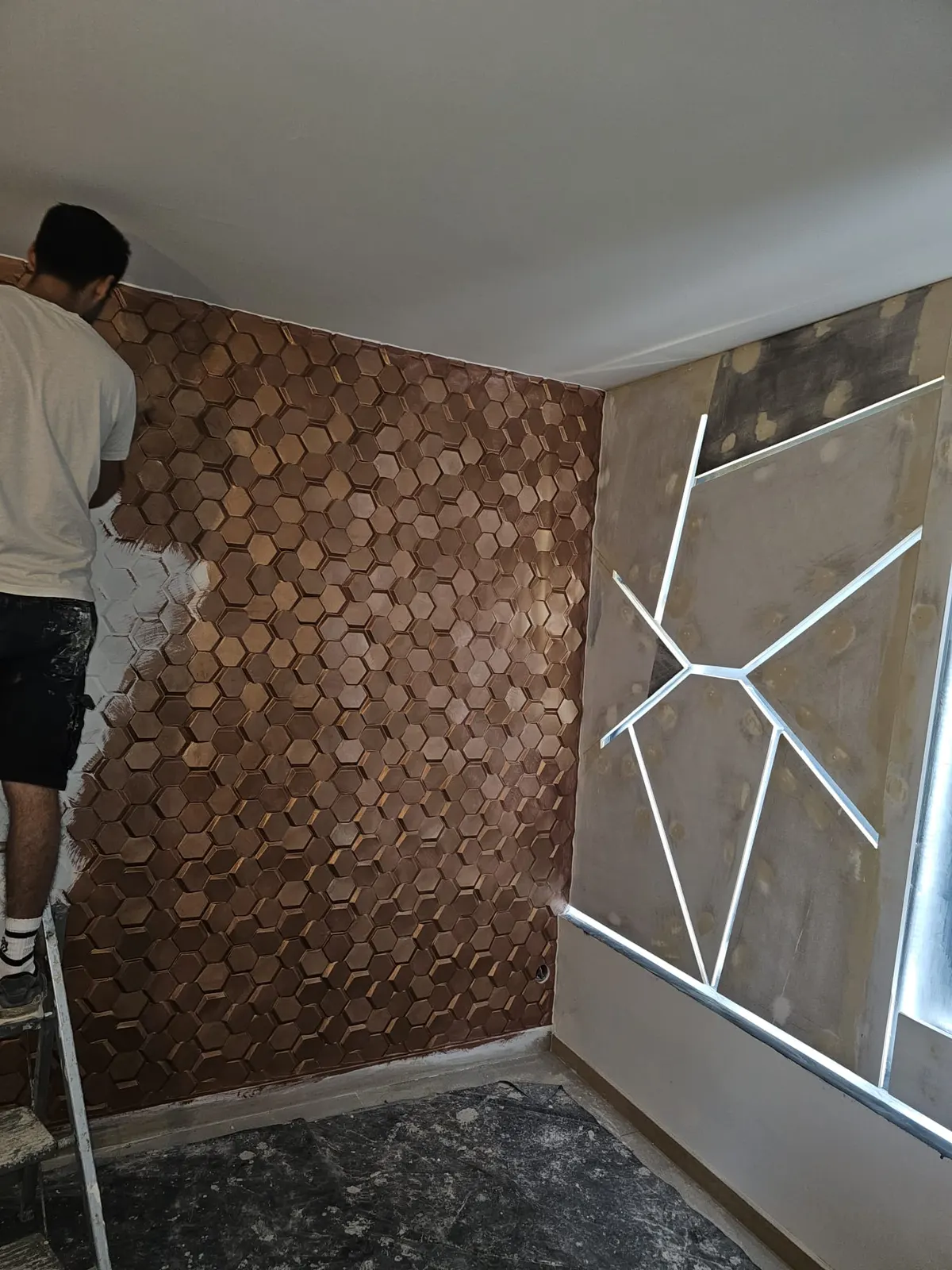 Pose d'un parement mural bois hexagonal en relief par un artisan