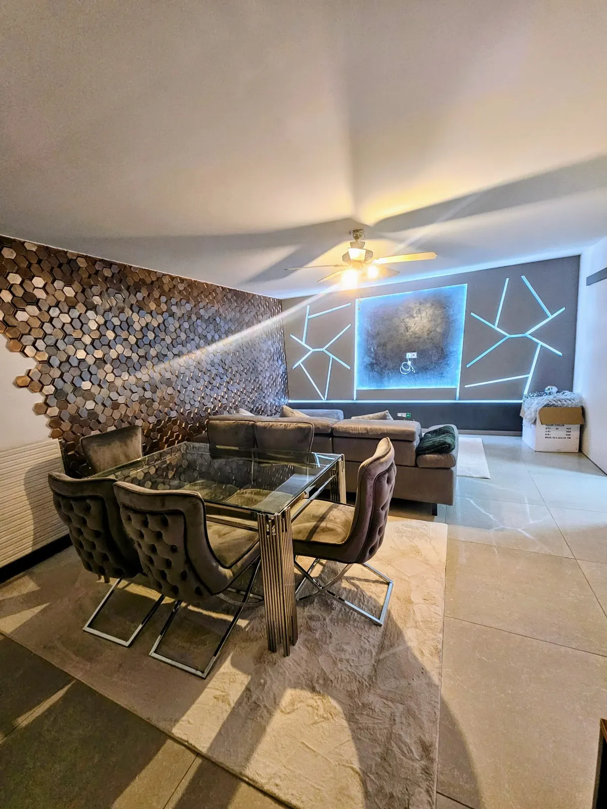 Salon rénové avec mur en parement bois doré, carrelage beige et éclairage LED décoratif