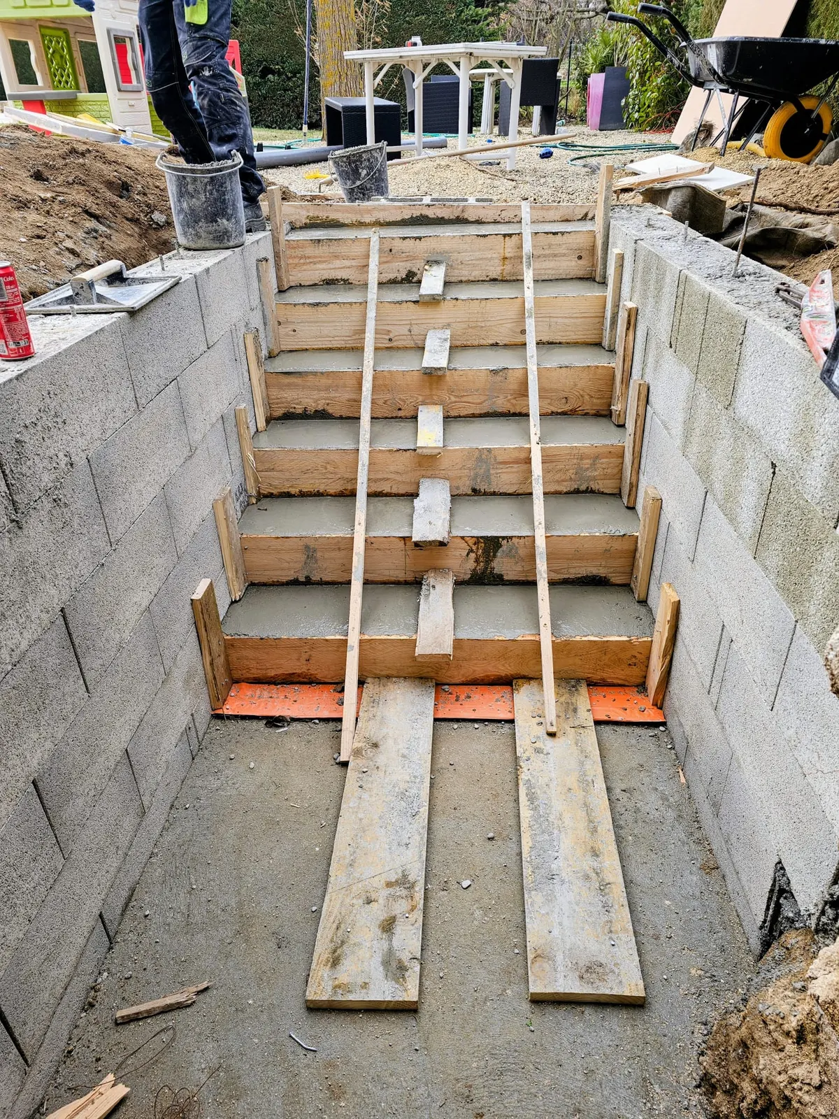 Construction d'un escalier extérieur en béton coffré entre deux murs de soutènement en parpaings