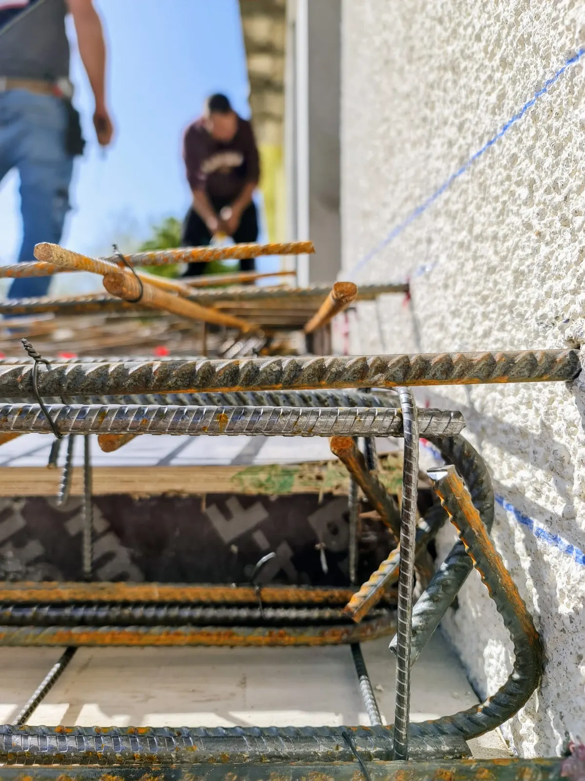 Ferraillage acier d'un chaînage béton armé en attente de coulage sur une façade en rénovation