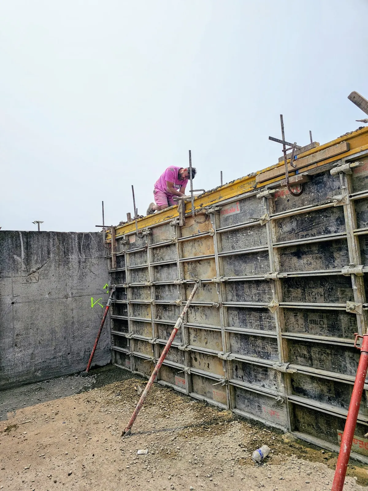 Ouvrier coffrant un mur en béton banché sur un chantier de gros œuvre