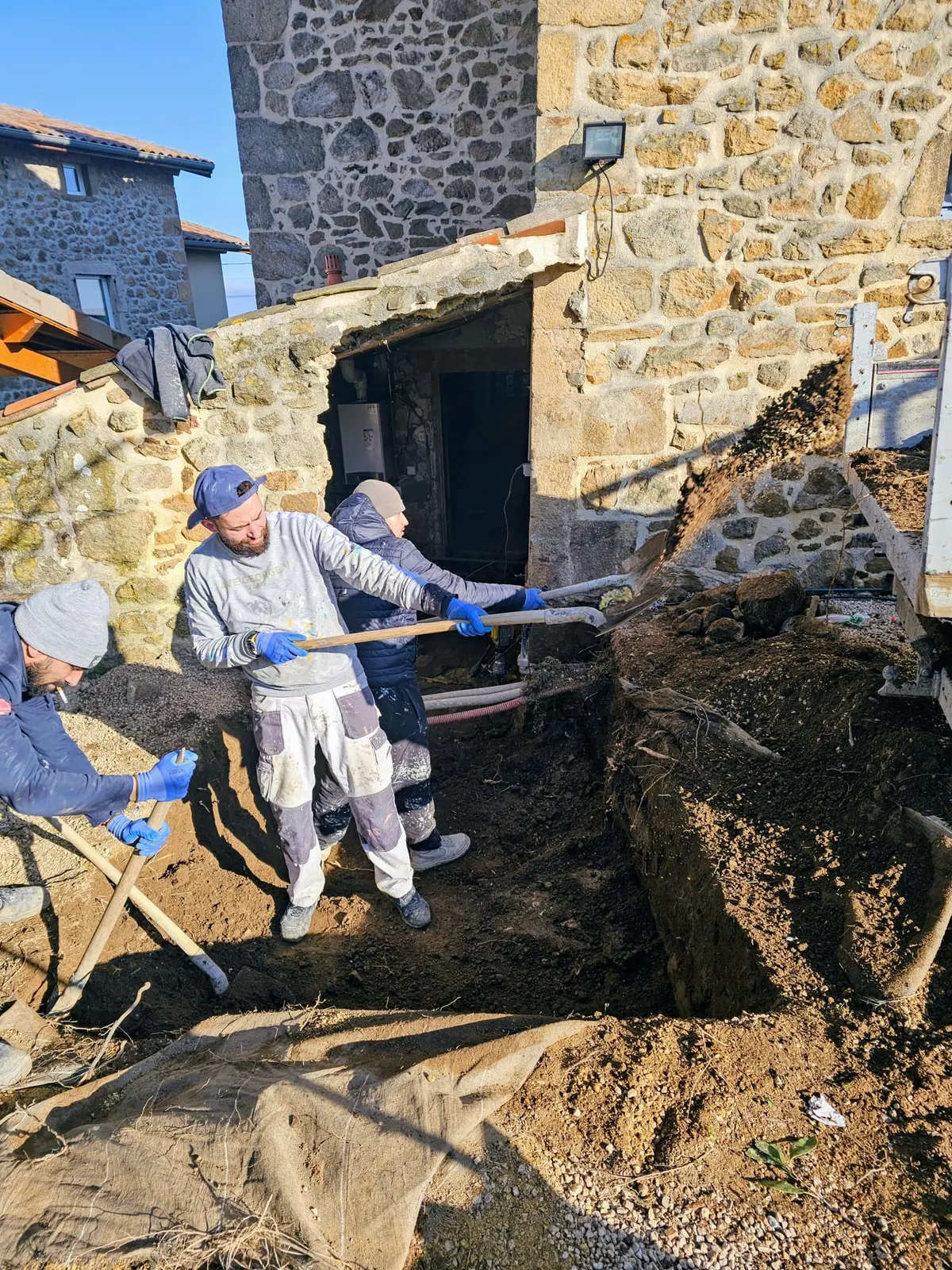 Terrassement en pied de mur en pierre lors de travaux de maçonnerie