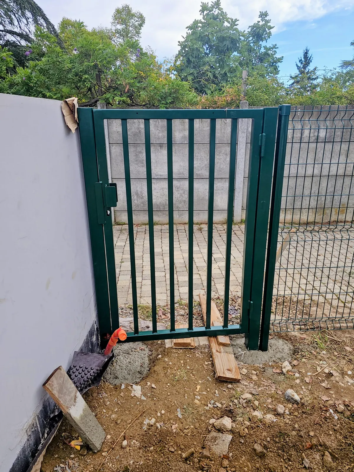 Pose d'un portillon de jardin vert sur scellement béton avec clôture grillagée