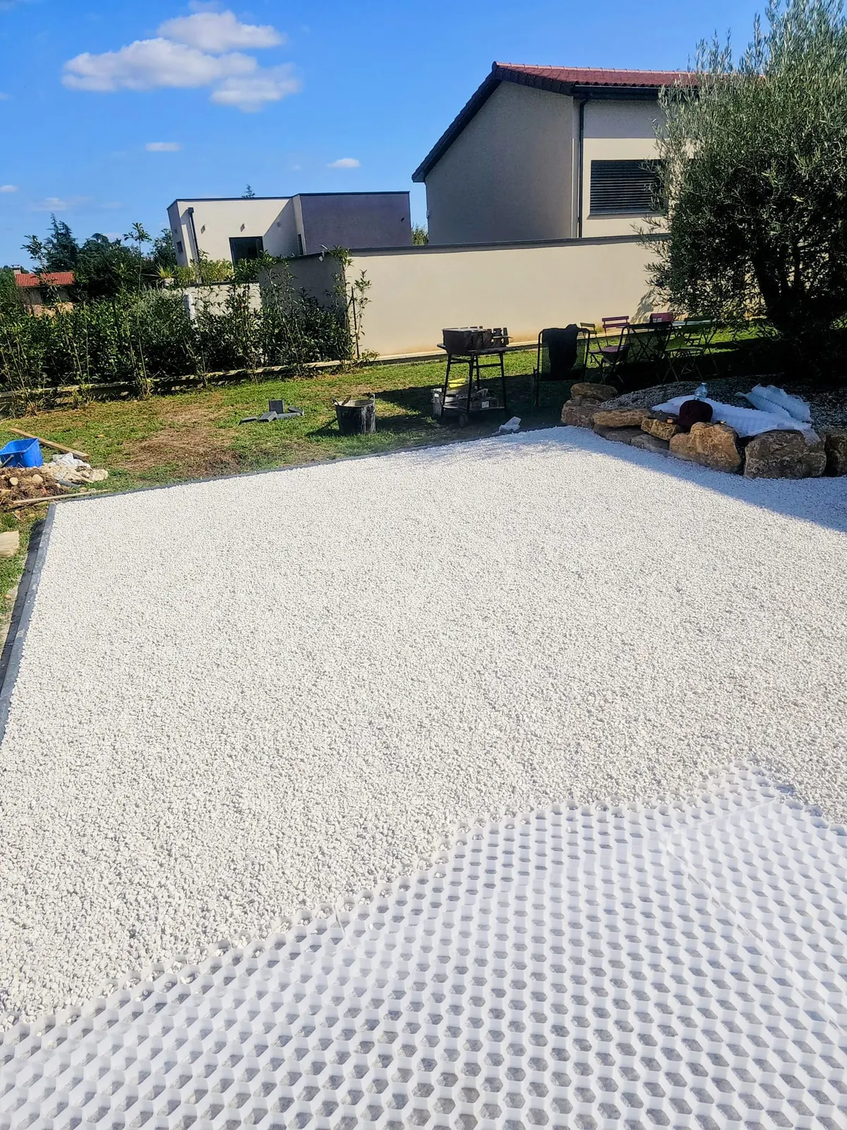 Aménagement extérieur en gravier blanc sur dalle stabilisatrice dans un jardin