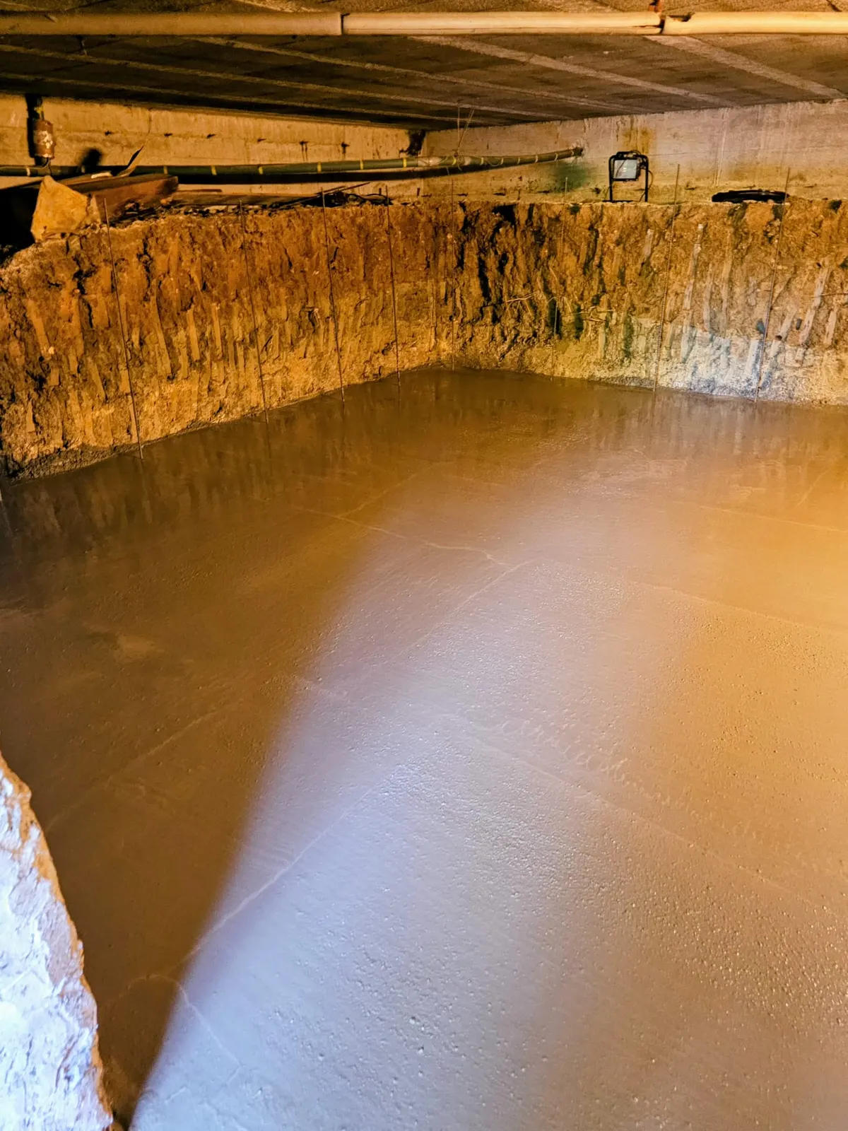 Dalle béton coulée dans un sous-sol avec plafond à solives bois
