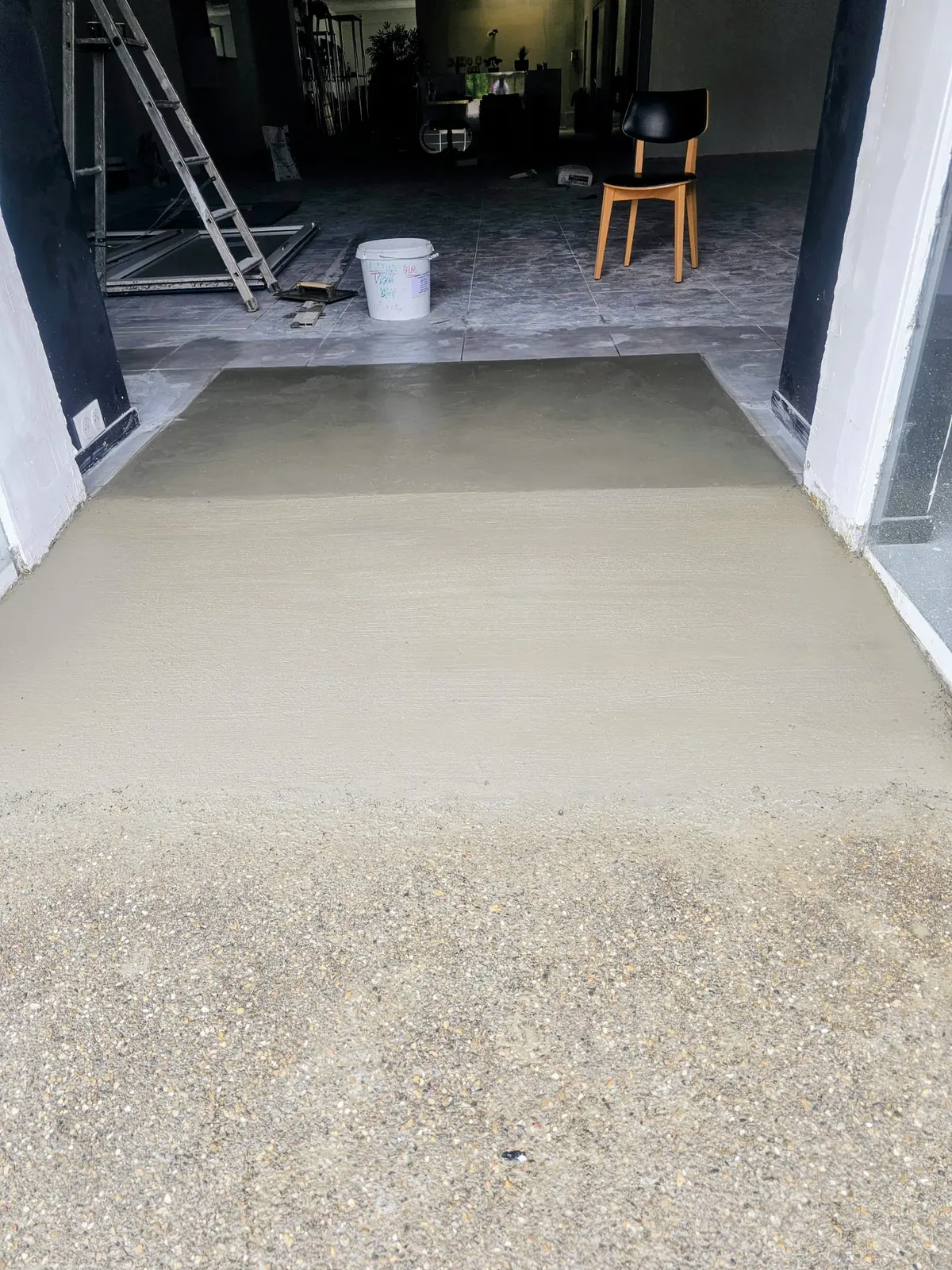 Chape béton fraîchement coulée au seuil d'une pièce en rénovation