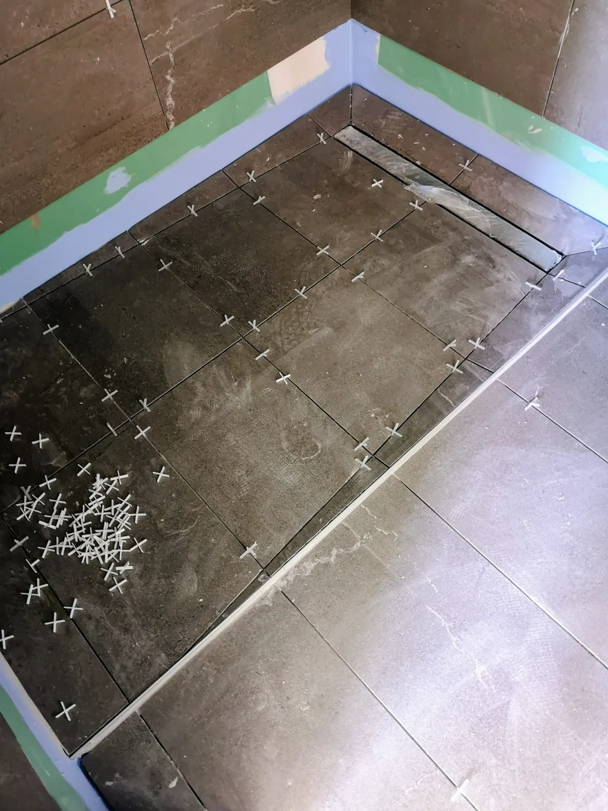 Pose de carrelage de sol gris avec croisillons en salle de bain
